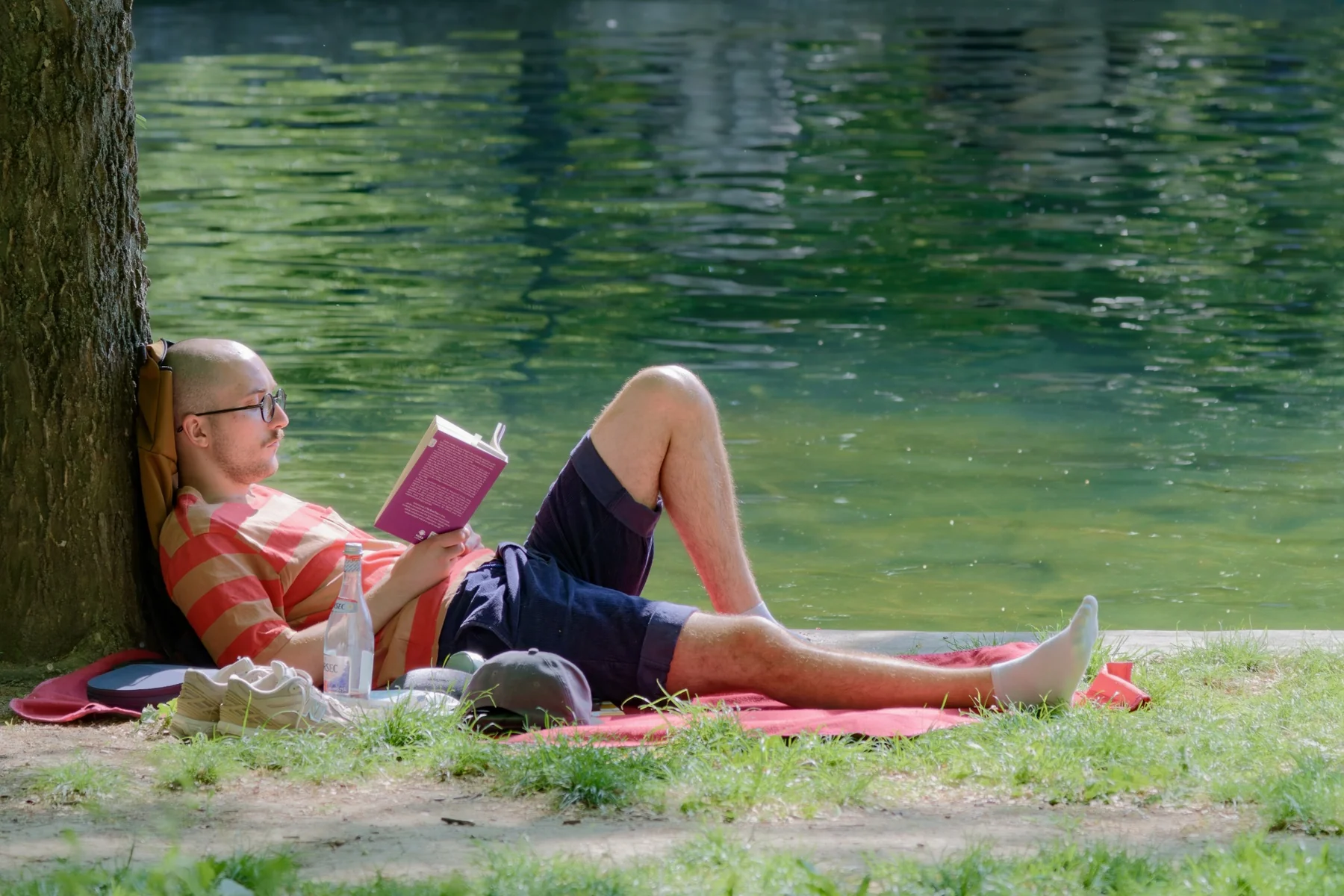 Reader taking a reflective pause outdoors by the water